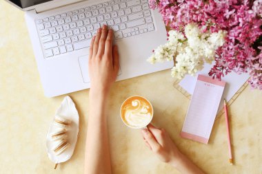 Çiçek ve elektronik cihazlar ile dokulu masa üzerinde Kadın eller.