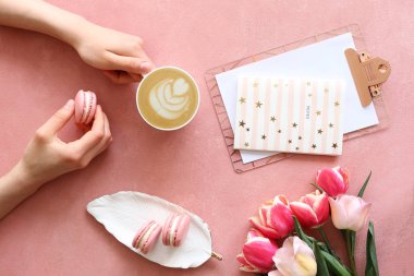 Renkli macaroon kurabiye ve kapuçino tutan kadın elleri ile güzel kompozisyon.