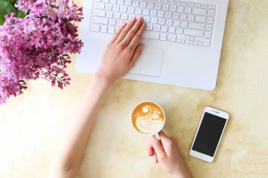 Beyaz dizüstü bilgisayar, beton dokulu masa arka plan üzerinde yazarak kadın üst görünüm. Çiçek buketi ile kadınsı çalışma alanı. Kapat, kopyalama alanı.