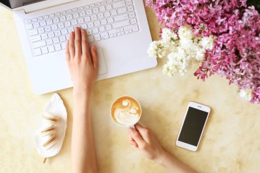 Beyaz dizüstü bilgisayar, beton dokulu masa arka plan üzerinde yazarak kadın üst görünüm. Çiçek buketi ile kadınsı çalışma alanı. Kapat, kopyalama alanı.