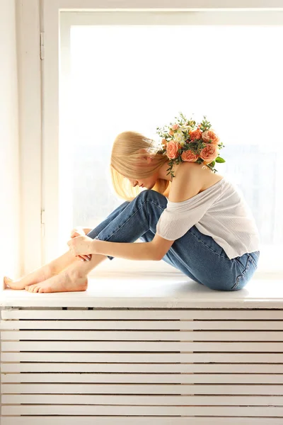 Junge blonde Frau in Mutti-Jeans und bauchfreiem Hemd mit einem Strauß Tulpen. — Stockfoto