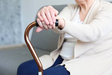 Sağlık sorunları olan yaşlı kadın baston üzerinde kollarını dinlenme.