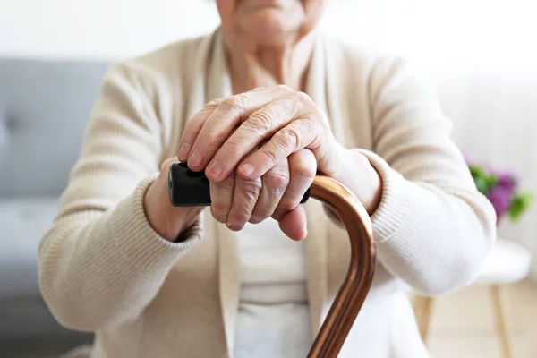 Mulher de idade com problemas de saúde descansando os braços na bengala . — Fotografia de Stock