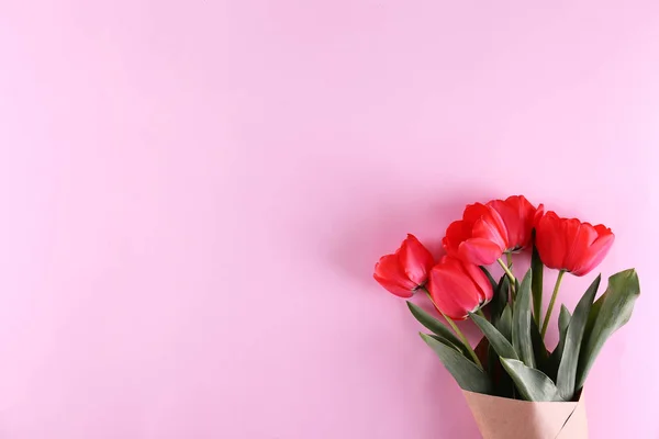 Composición minimalista con ramo de tulipanes rojos en envoltura de papel . — Foto de Stock