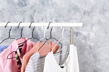 Kadın kalçalı giyim mağazasının iç mekanı. Alışveriş merkezindeki hippi moda şovu odasında askıda asılı renkli kadın kıyafetleri. Çamurlu beton arka plan. Boşluğu kopyala.