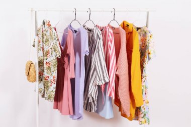 Kadın kalçalı giyim mağazasının iç mekanı. Alışveriş merkezindeki hippi moda şovu odasında askıda asılı renkli kadın kıyafetleri. Beyaz duvar arka planı. Boşluğu kopyala.