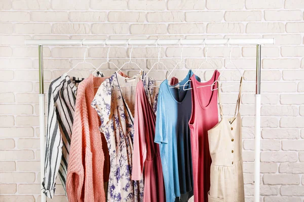 Women's hip clothing store interior concept. Row of different colorful female clothes hanging on rack in hipster fashion show room in shopping mall. White brick wall background. Copy space. — Stock Photo, Image