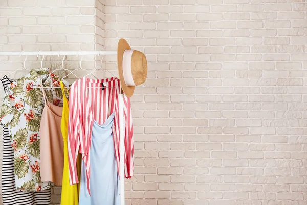 Women's hip clothing store interior concept. Row of different colorful female clothes hanging on rack in hipster fashion show room in shopping mall. White brick wall background. Copy space. — Stock Photo, Image