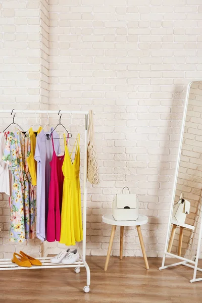 Roupas femininas loja de roupas conceito interior. Fila de roupas femininas coloridas diferentes penduradas no rack na sala de desfile de moda hipster no shopping center. Fundo de parede de tijolo branco. Espaço de cópia . — Fotografia de Stock