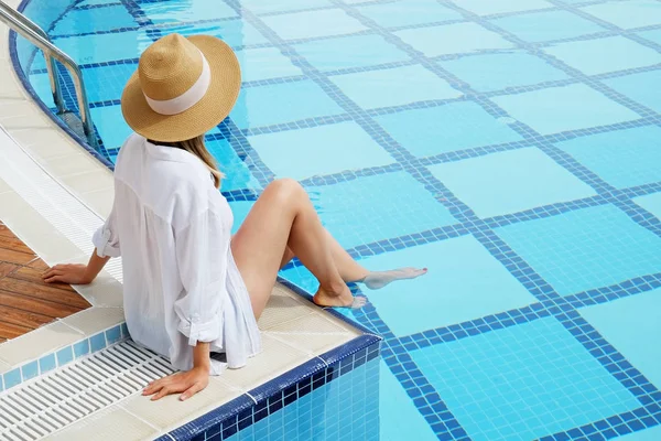 Oigenkännlig kaukasisk kvinna med Fit Body bär blå bikini baddräkt och breda brädden halm hatt som täcker hennes ansikte kylning i en swimmingpool. Kopiera utrymme, uppifrån, fyrkantigt mönster. — Stockfoto