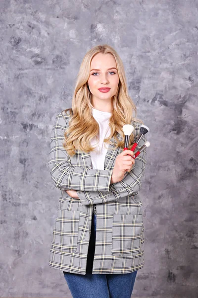 Professional visagiste posing with her equipment over grunged concrete wall background — Stock Photo, Image