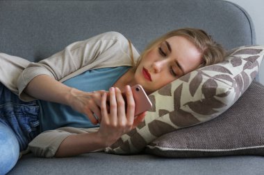 Üzgün kız cep telefonu ile evde allone oturan.