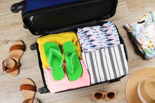 Plastic hardshell suitcase packed with casual clothing items.