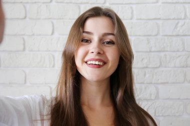 Pembe gömlek giyen ve gülümseyen esmer genç kadın.