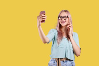 Pembe saçlı toner parlak renkli izole arka plan üzerinde poz ve akıllı telefon tutan genç güzel sarışın kadın. Duyguları gösteren genç kadın modelin portresi. Kapat, kopyalama alanı.