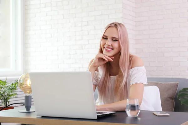 Jeune belle femme blonde avec des cheveux roses toner assis dans son lieu de travail avec ordinateur portable blanc. Portrait de mannequin adolescente dans l'intérieur du bureau d'angle. Gros plan, espace de copie, fond . — Photo