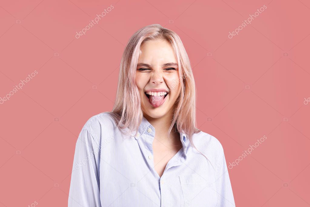 Young beautiful blonde woman with pink hair toner posing over bright colorful isolated background. Portrait of teenage female model showing emotions. Close up, copy space.
