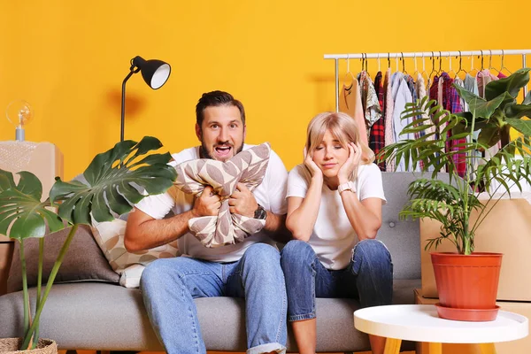 Casal jovem em roupas combinando se divertindo caixas móveis, isolado em amarelo . — Fotografia de Stock