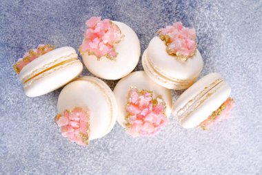 Grunged beton doku arka plan üzerinde pembe kristal şeklinde marmelat dekorasyon ile beyaz fransız makarna tatlılar demet minimalist kompozisyon. Üstten görünüm, yakın çekim, düz döşeme, kopyalama alanı.