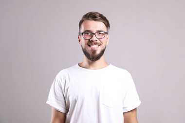 Gri arka planda poz veren mükemmel bakımlı sakallı bir adam..