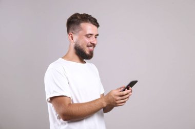 Gri arka planda poz veren mükemmel bakımlı sakallı bir adam..