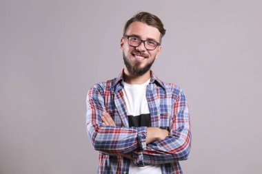 Gri arka planda poz veren mükemmel bakımlı sakallı bir adam..