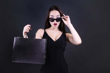 Young beautiful woman with paper bag on dark background. clipart