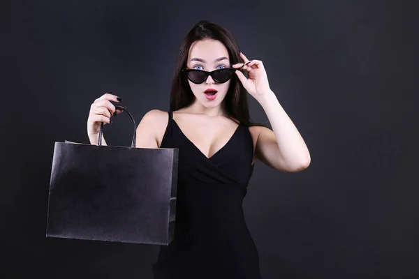 Young beautiful woman with paper bag on dark background. — Stock Photo, Image