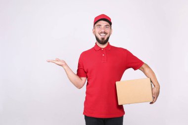Kurye teslimat konsepti. Kırmızı polo tişörtlü sakallı adam paketi tutuyor..