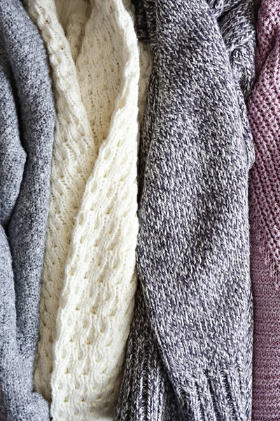 Pile of knitted sweaters of different colors and patterns perfectly stacked.