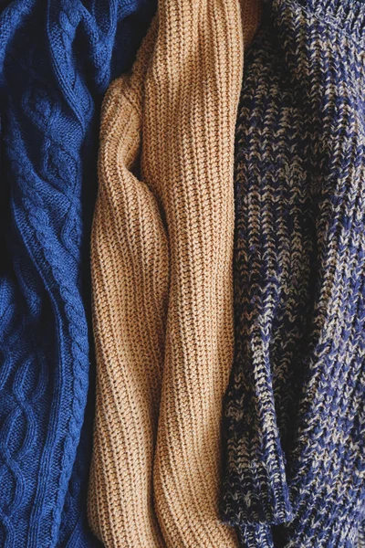 Hromada pletených svetrů různých barev a vzorů dokonale skládaných. — Stock fotografie