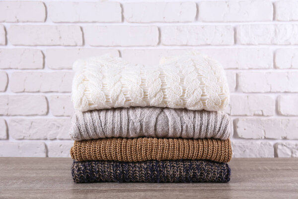 Куча трикотажных свитеров разных цветов и узоров, идеально сложенных
.