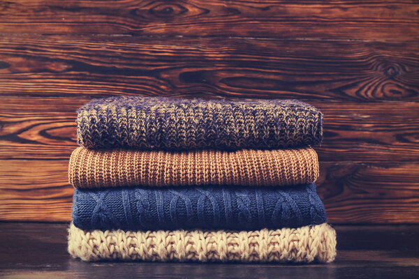 Pile of knitted sweaters of different colors and patterns perfectly stacked.