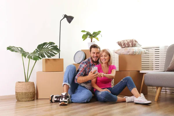 Joven pareja casada mudándose en nuevo apartamento, sentado en el flo — Foto de Stock