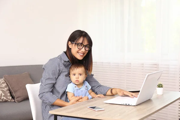 Mladá matka pracuje doma kancelář se svým dítětem, bílá zeď pozadí s kopírovacím prostorem. — Stock fotografie