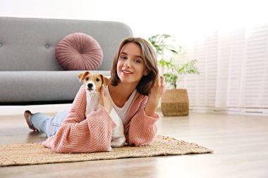 Genç ve güzel hippi kadının portresi ve dört aylık sevimli köpeği Jack Russell Terrier evde, oturma odasında güneş ışığıyla dolu. Lofty iç arkaplan, kapat, kopyala boşluk.