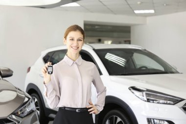 Bir grup araba ve satış temsilcisinin bulunduğu geniş bir otomobil galerisi.