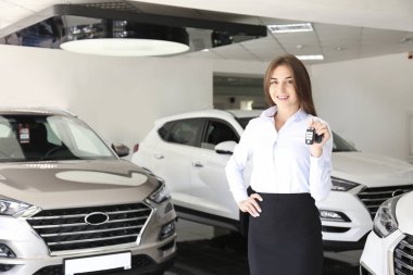 Bir grup araba ve satış temsilcisinin bulunduğu geniş bir otomobil galerisi.