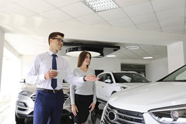 Bir grup araba ve satış temsilcisinin bulunduğu geniş bir otomobil galerisi.
