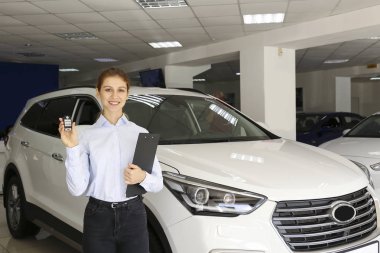 Bir grup araba ve satış temsilcisinin bulunduğu geniş bir otomobil galerisi.