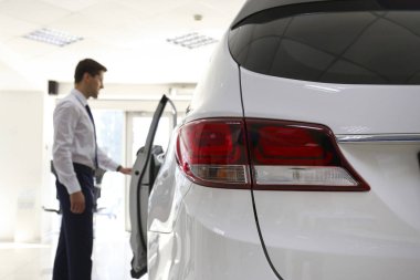 Bir grup araba ve satış temsilcisinin bulunduğu geniş bir otomobil galerisi.