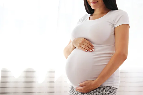 Young woman holding her pregnant belly on ninth month of pregnancy. — Stock Photo, Image