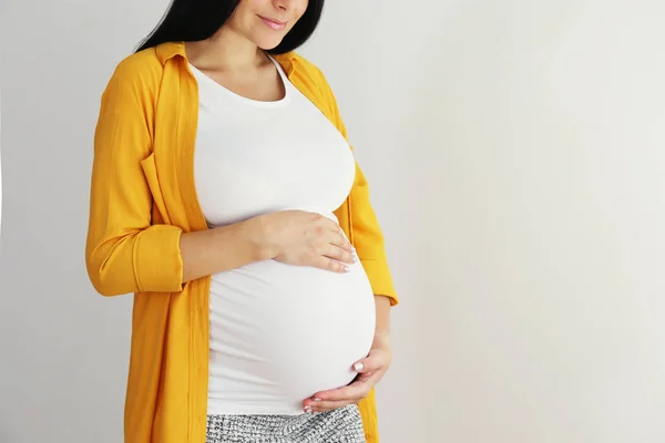 Junge Frau hält ihren schwangeren Bauch im neunten Monat der Schwangerschaft. — Stockfoto