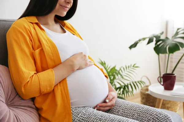 Mladá žena drží její těhotné břicho v devátém měsíci těhotenství. — Stock fotografie