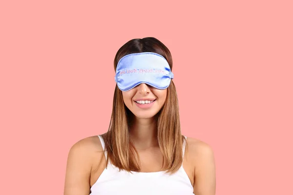 Smiling woman wearing blue sleeping patch on pink background. — Stock Photo, Image