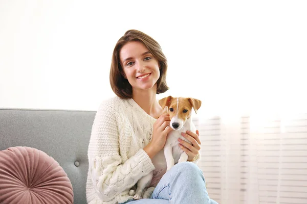 Retrato de una joven mujer hipster hermosa con su adorable cachorro Jack Russell terrier de cuatro meses de edad en casa en la sala de estar llena de luz natural del sol. Fondo interior elevado, primer plano, espacio para copiar . — Foto de Stock