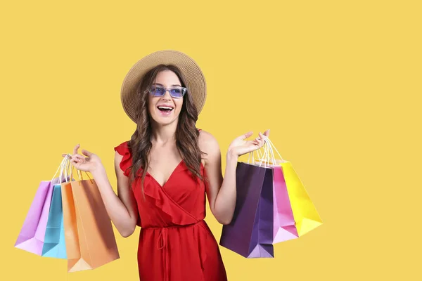 Black Friday Saison Verkaufskonzept. attraktive junge Frau mit langen brünetten Haaren, mit Strohhut und vielen verschiedenen leeren Einkaufstaschen vor gelbem Hintergrund. Kopierraum, Nahaufnahme — Stockfoto