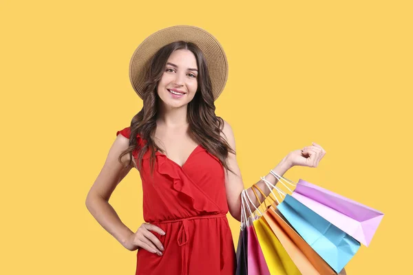 Conceito de venda de sexta-feira negra. Jovem atraente com cabelos longos morena, usando chapéu de palha, segurando muitos sacos de compras em branco diferentes sobre fundo isolado amarelo. Espaço de cópia, close up — Fotografia de Stock