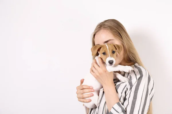 El más lindo de dos meses de edad Jack Russel terrier cachorro con hermosa rubia joven. Pequeño perrito adorable con manchas de piel divertida acostado con el propietario. Primer plano, espacio de copia, fondo aislado . — Foto de Stock