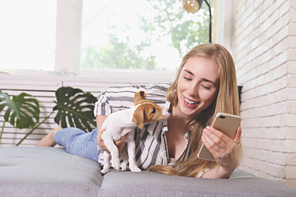 The cutest two months old Jack Russel terrier puppy with beautiful blonde young woman. Small adorable doggy with funny fur stains lying with owner. Close up, copy space, isolated background.